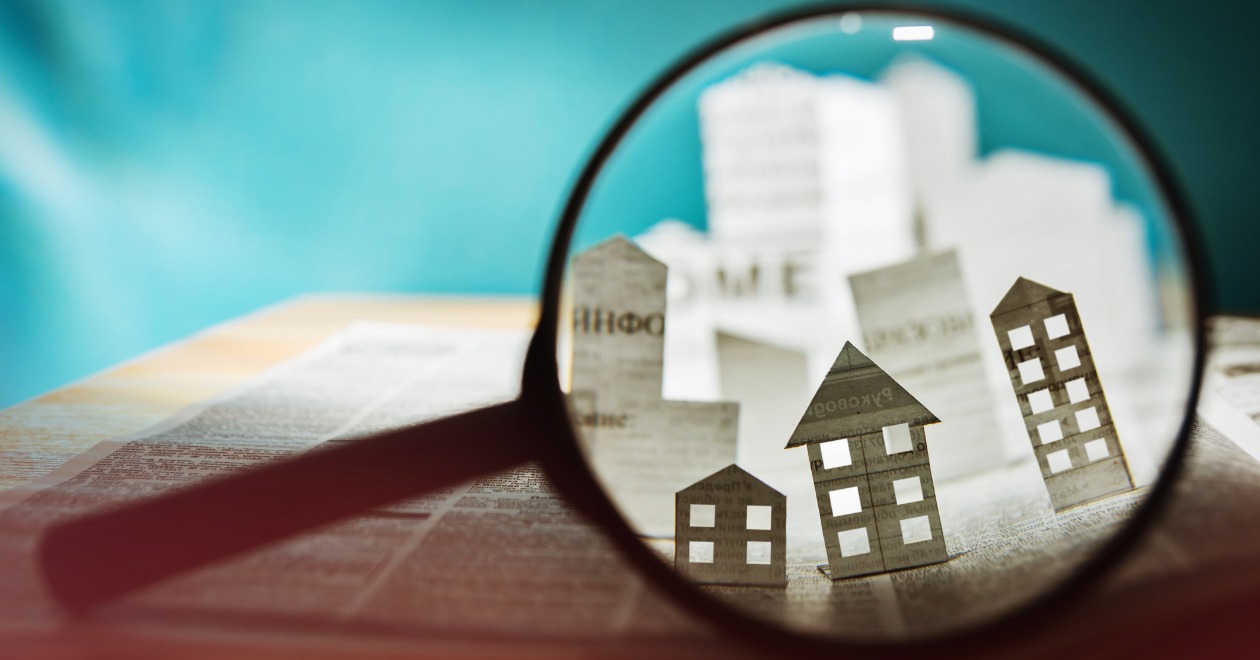 Paper houses under magnifying glass