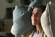 Woman with cushions covering her ears 