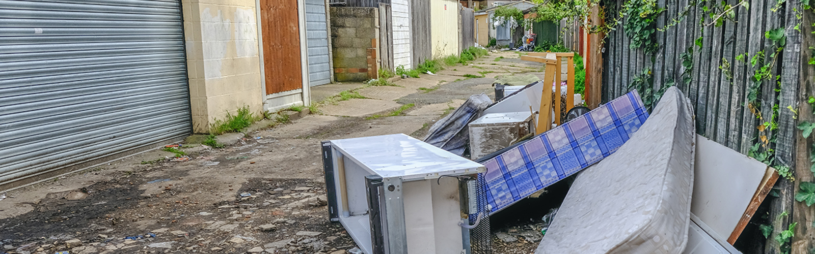 Household items discarded next to row of garages 