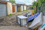 Household items discarded next to row of garages