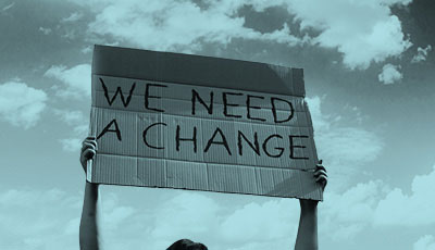 A person holding up a sign that says 'We need a change'