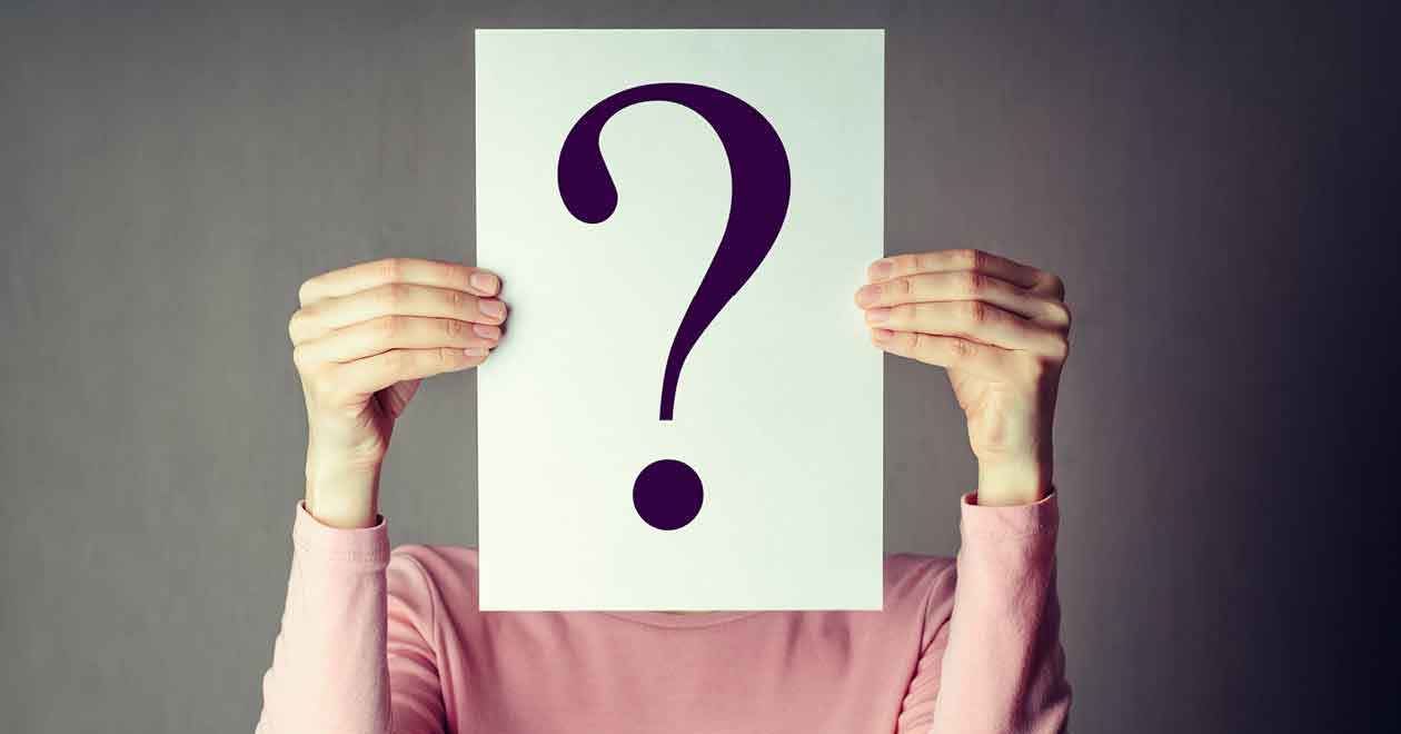 A woman holds up a piece of paper with a question mark