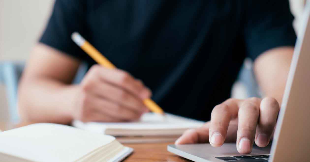 A person takes notes while completing online training