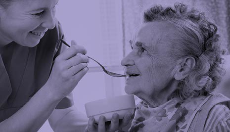 Older lady being fed by a nurse