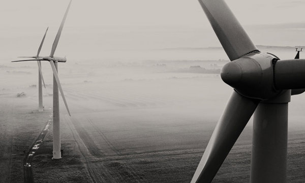Three wind turbines in a misty field. 