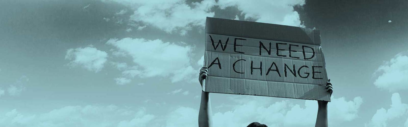 A person holding up a sign that says 'We need a change'