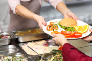Canteen staff handing food to child