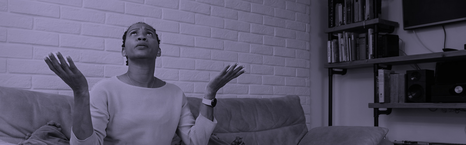 Person sitting on a sofa with arms raised and looking upwards