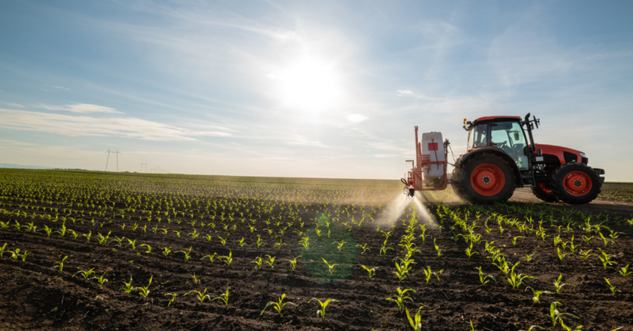 Tractor spraying pesticide on crops