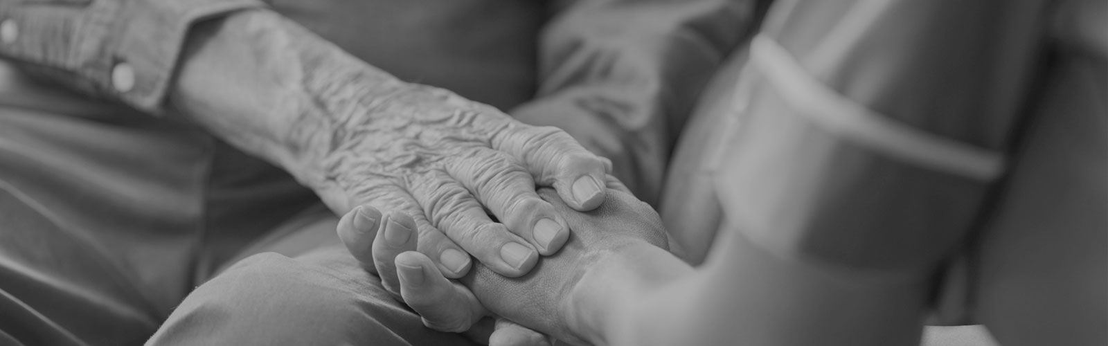 Care worker in uniform holding the hands of a resident