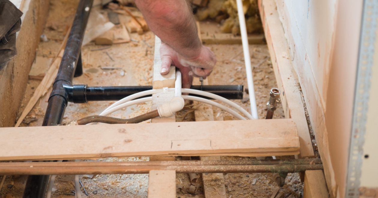 A plumber installing the pipe work for underfloor heating at a house in the UK